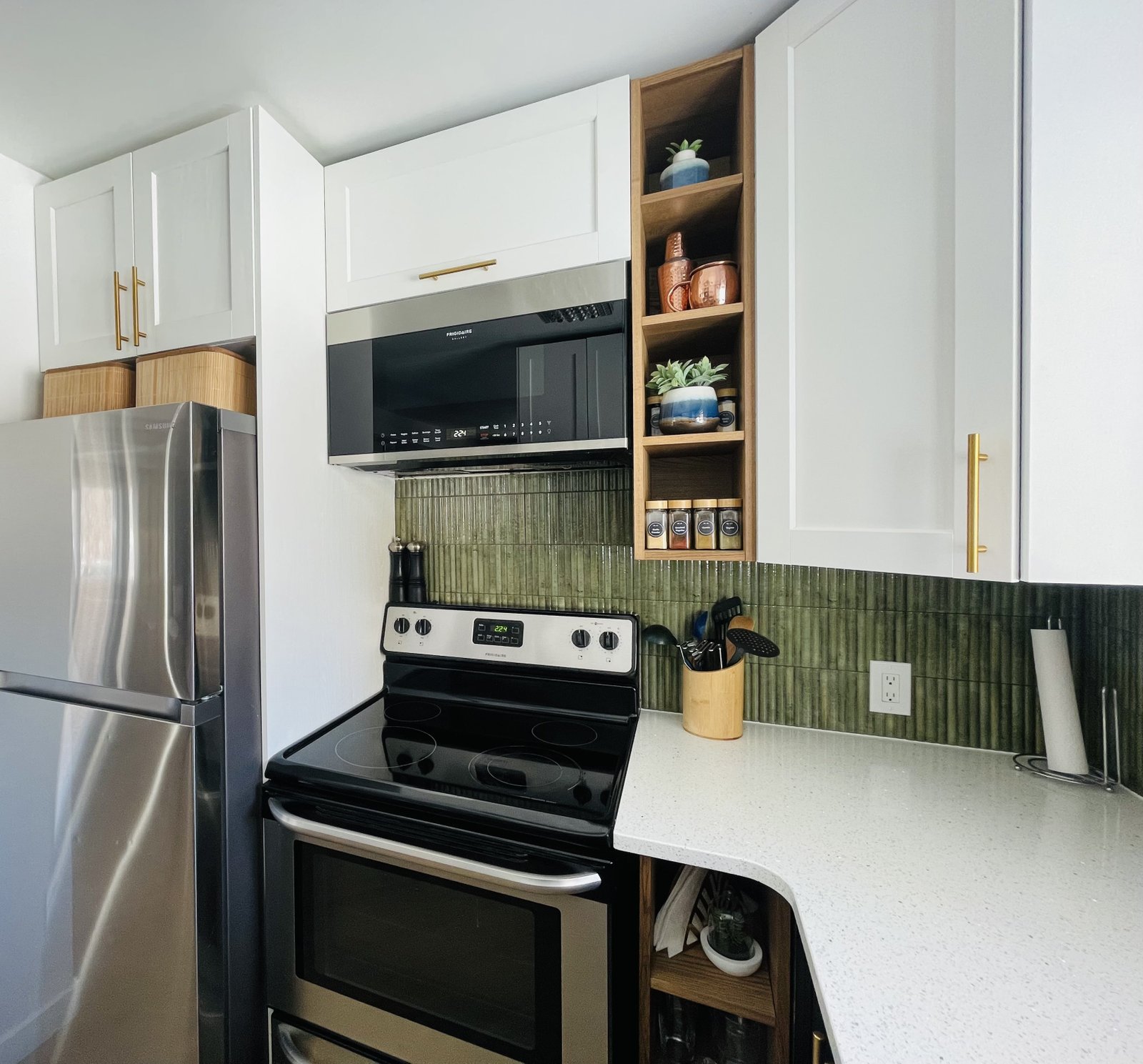 Kitchen with white cabinets, gold hardware and green tile backsplash with added wood open storage shelves